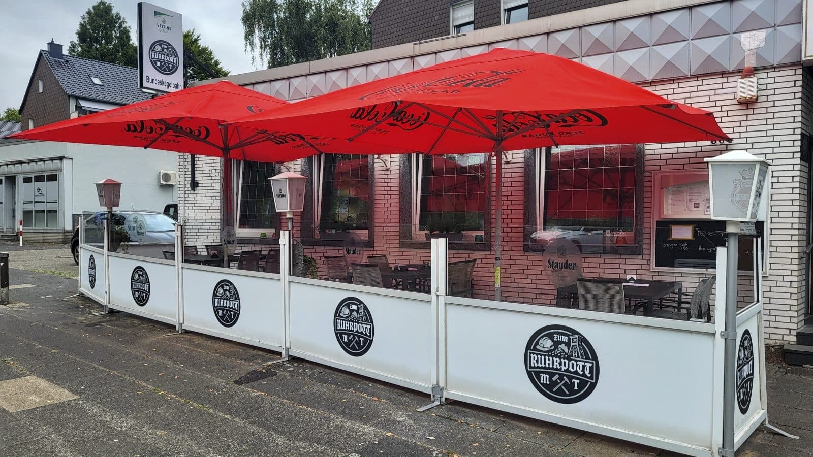 Biergarten mit roten Sonnenschirmen vor der Gaststätte